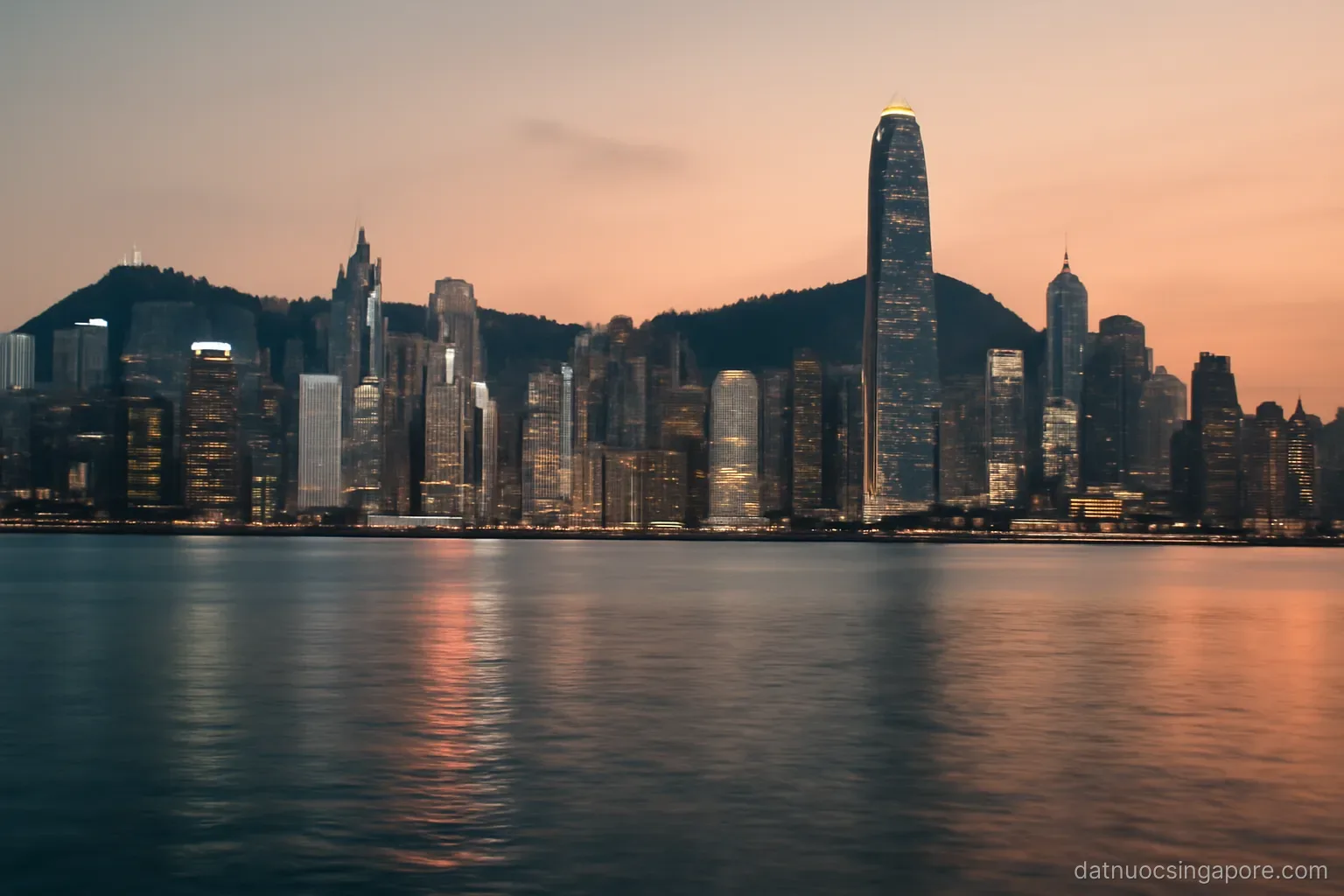 a dense skyline of high-rise towers seen across a calm harbour at dusk, wide panorama
